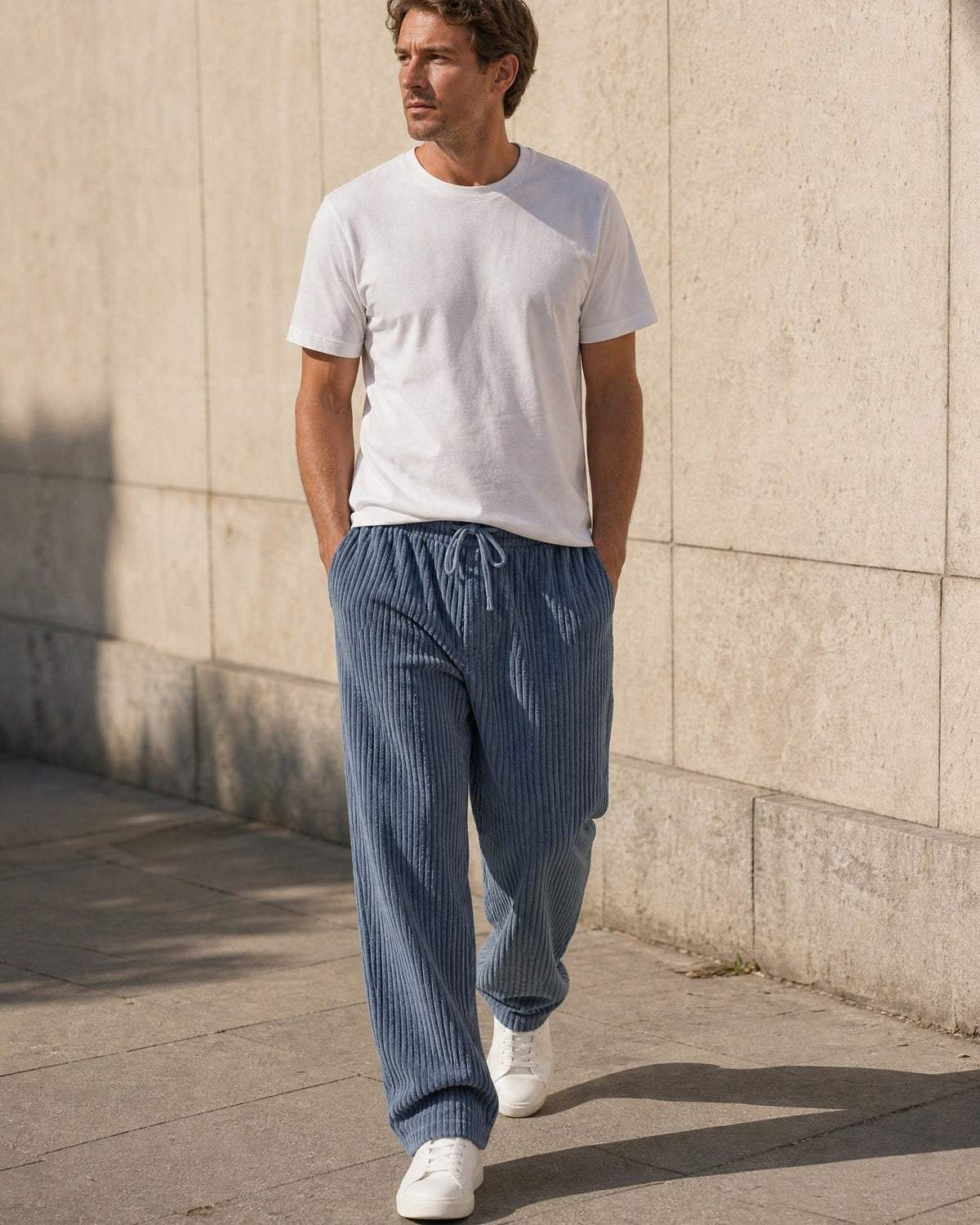 Wexford corduroy trousers in Blue, walking along a city street